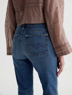 Person wearing blue jeans and a brown jacket on a white background