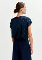 Woman wearing a navy blue dress with a patterned top on a white background