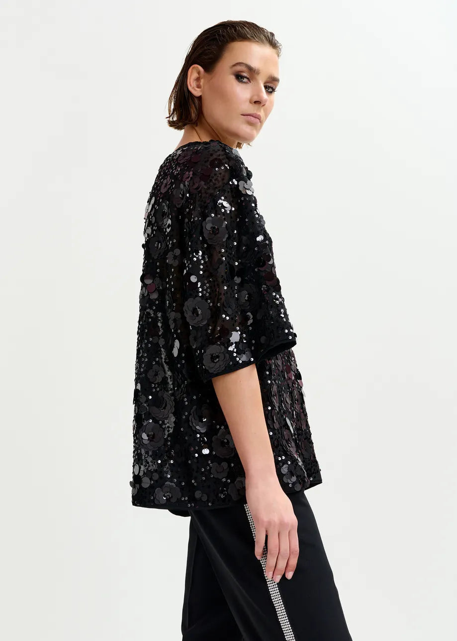 Woman wearing a black sequin top on a white background