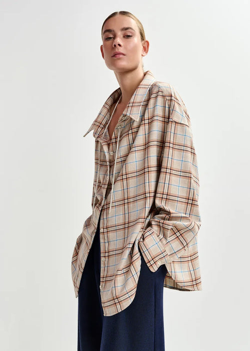 Person wearing a plaid shirt with a neutral background