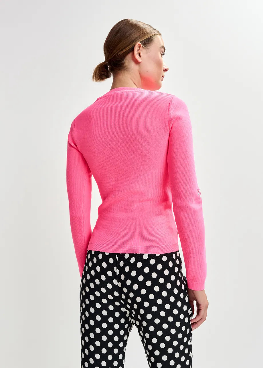Person wearing a pink sweater and black polka dot pants on a light gray background