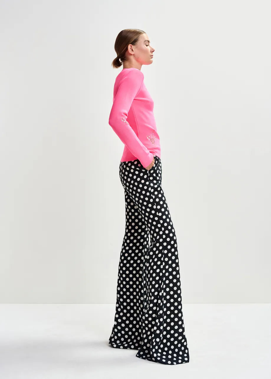 Woman wearing a pink top and black polka dot pants on a white background