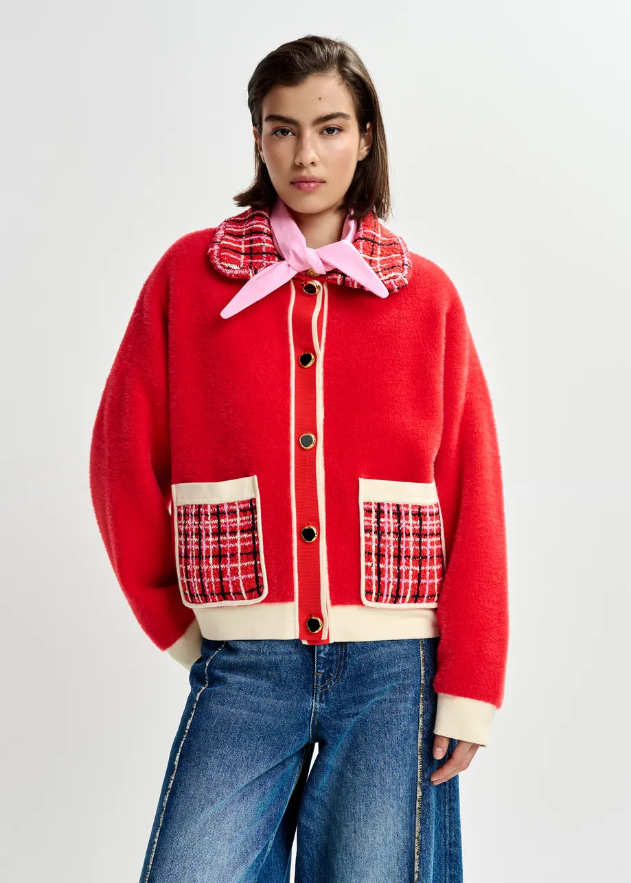 Person wearing a red jacket with plaid accents on a white background