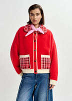 Person wearing a red jacket with plaid accents on a white background