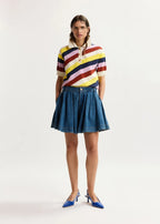 Woman wearing a colorful striped shirt and denim skirt on a white background