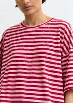 Person wearing a red and white striped shirt with small dots on a plain background