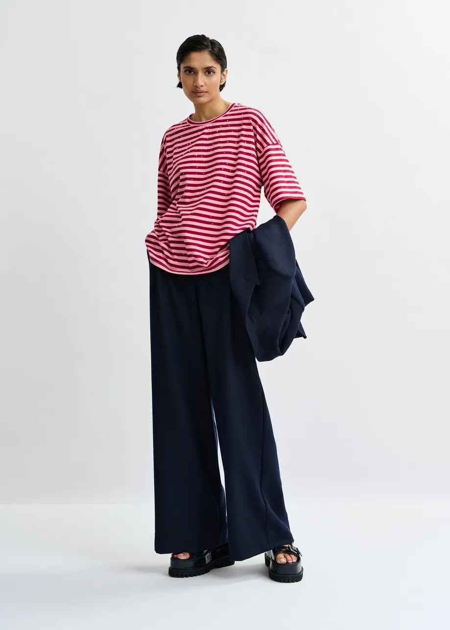 Person wearing a red and white striped shirt with navy pants on a white background