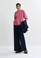 Person wearing a red and white striped shirt with navy pants on a white background