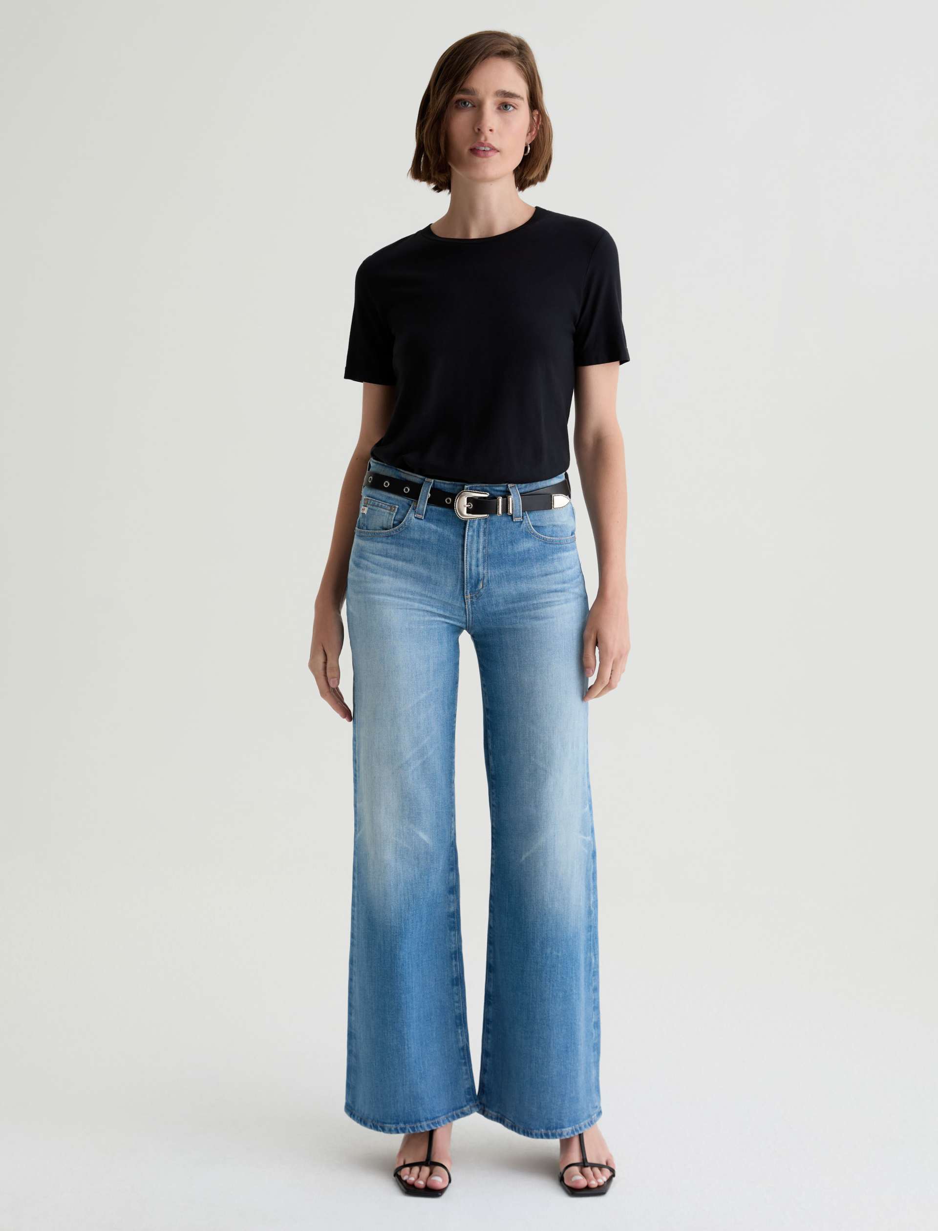 Woman wearing a black t-shirt and blue jeans on a white background