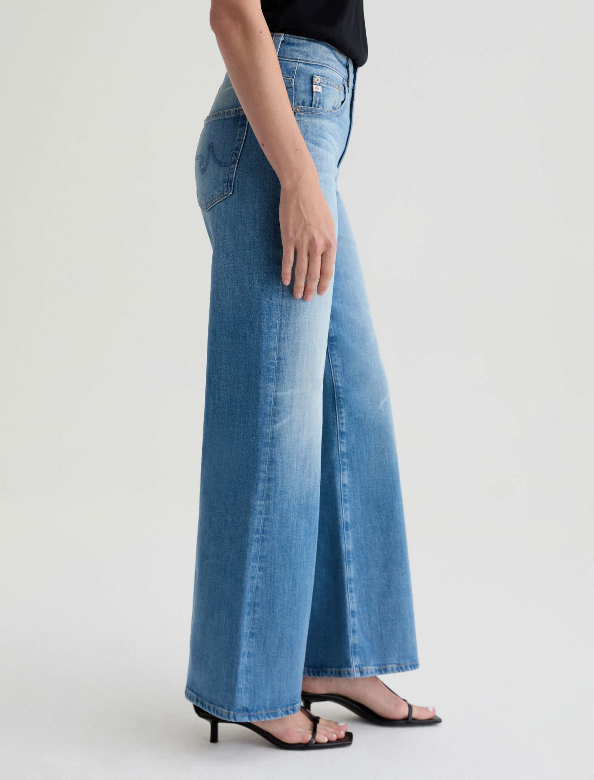 Person wearing blue wide-leg jeans on a white background