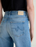 Blue jeans with a brand label on the back pocket against a neutral background