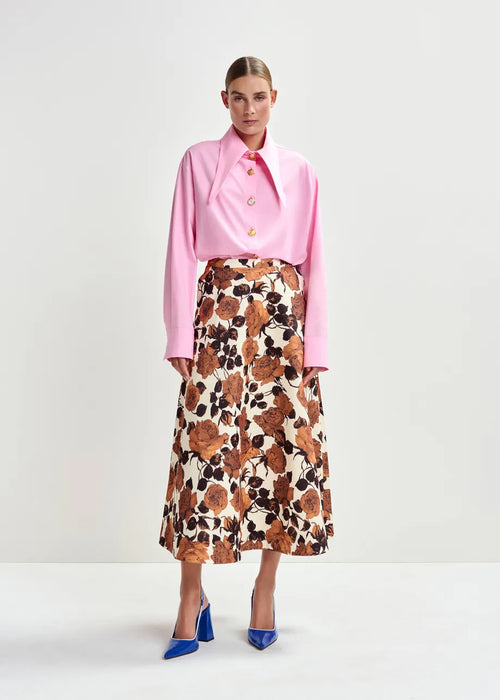 Woman wearing a pink blouse and floral skirt on a white background