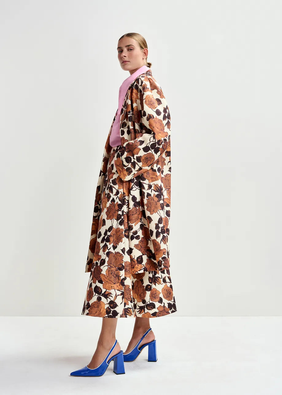 Woman wearing a floral dress with a pink blouse and blue shoes on a white background