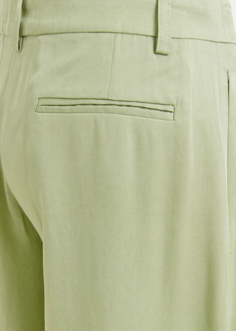 Close-up of light green pants with a pocket detail