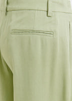 Close-up of light green pants with a pocket detail