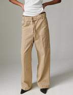 Person wearing beige pants and a white shirt on a plain background