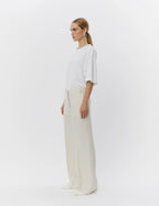 Woman wearing a white top and beige pants on a white background