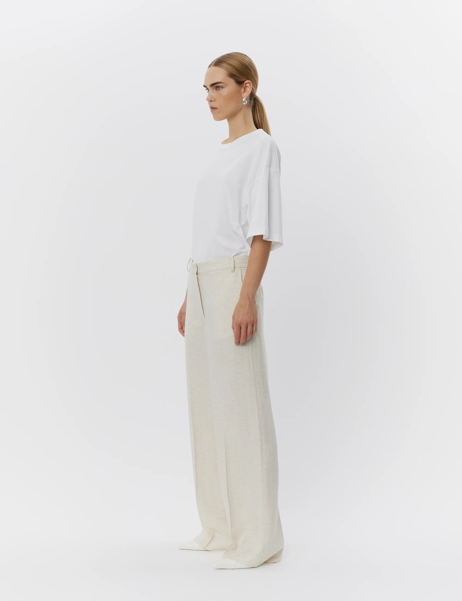 Woman wearing a white top and beige pants on a white background