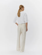 Person wearing a white shirt and beige pants on a white background