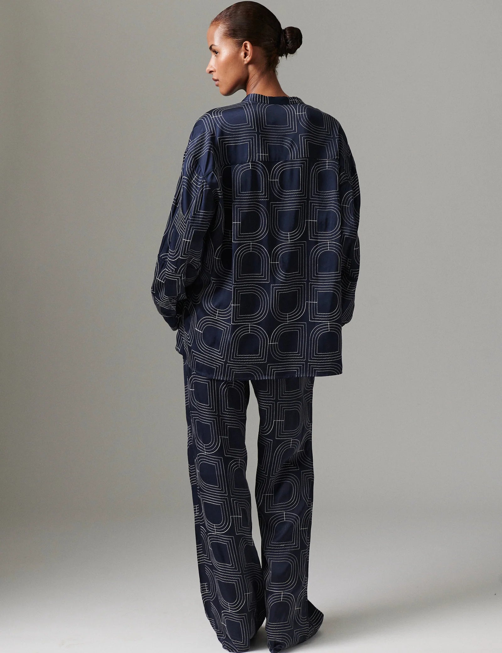 Person wearing a dark blue patterned outfit on a plain background