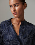 Woman wearing a navy blue shirt with white geometric patterns against a gray background