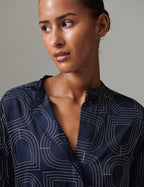 Woman wearing a navy blue shirt with white geometric patterns against a gray background