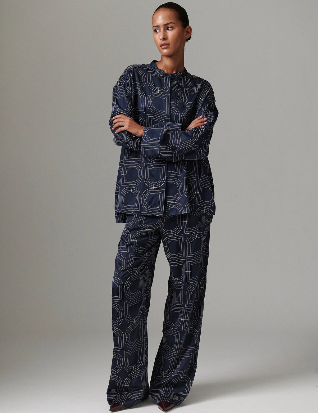 Person wearing a dark blue patterned outfit on a plain background
