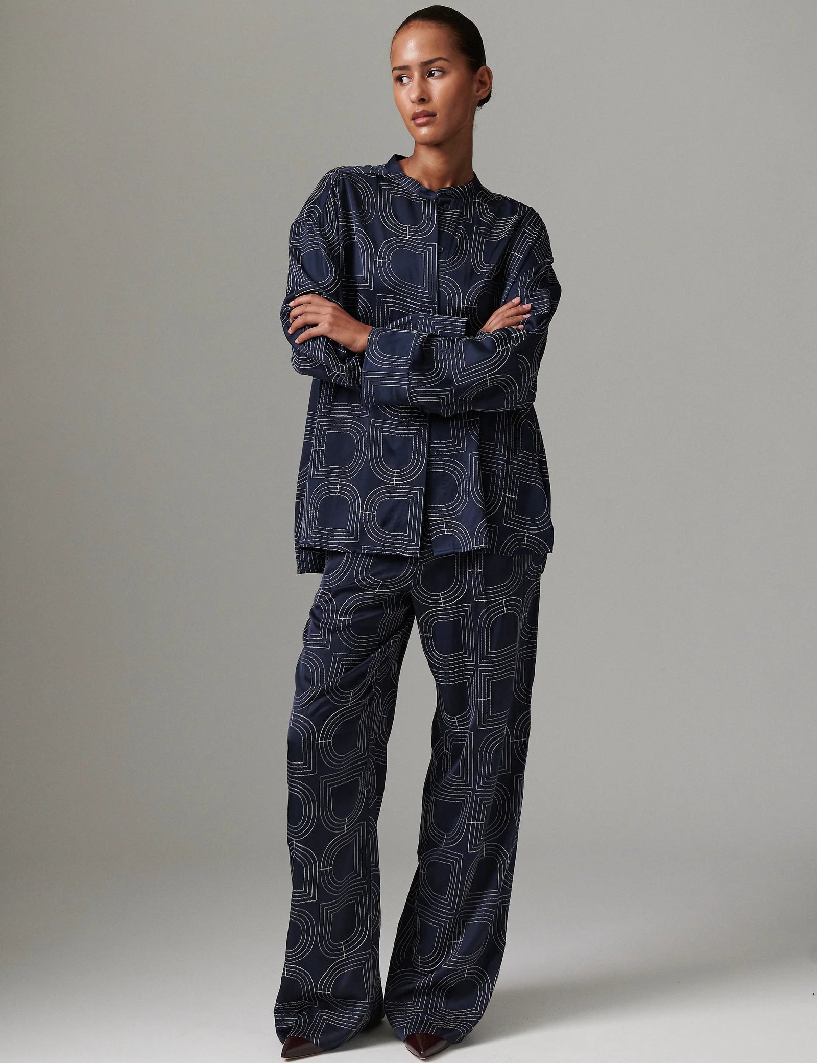 Person wearing a dark blue patterned outfit on a plain background