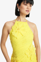 Woman wearing a yellow dress with floral details on a white background