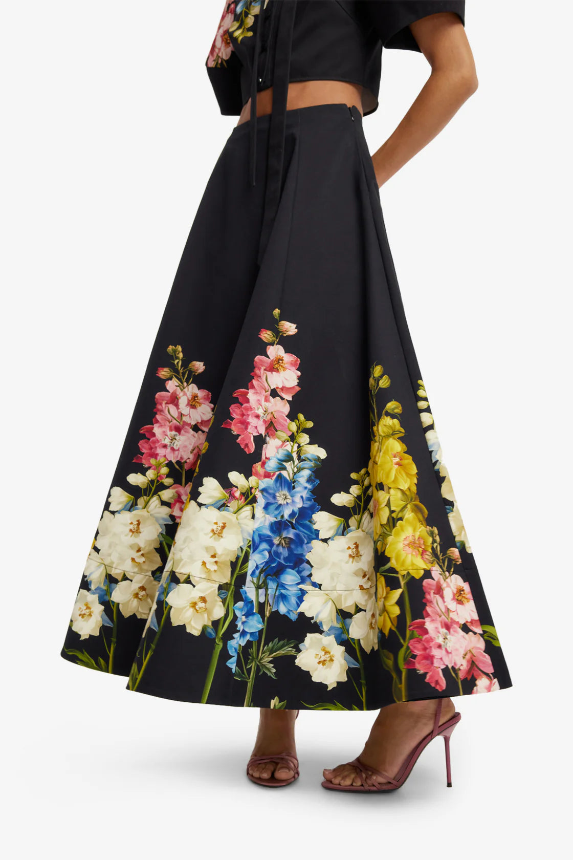 Black floral skirt with colorful flowers worn by a person on a white background