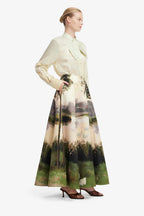 Woman wearing a long, patterned skirt with a white blouse on a white background