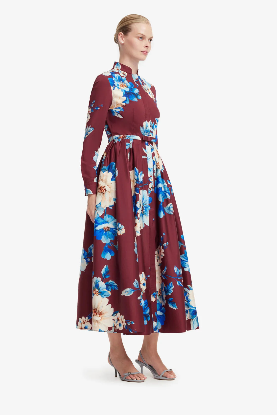 Woman wearing a burgundy dress with floral pattern on a white background