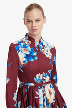 Woman wearing a maroon dress with blue floral pattern on a white background