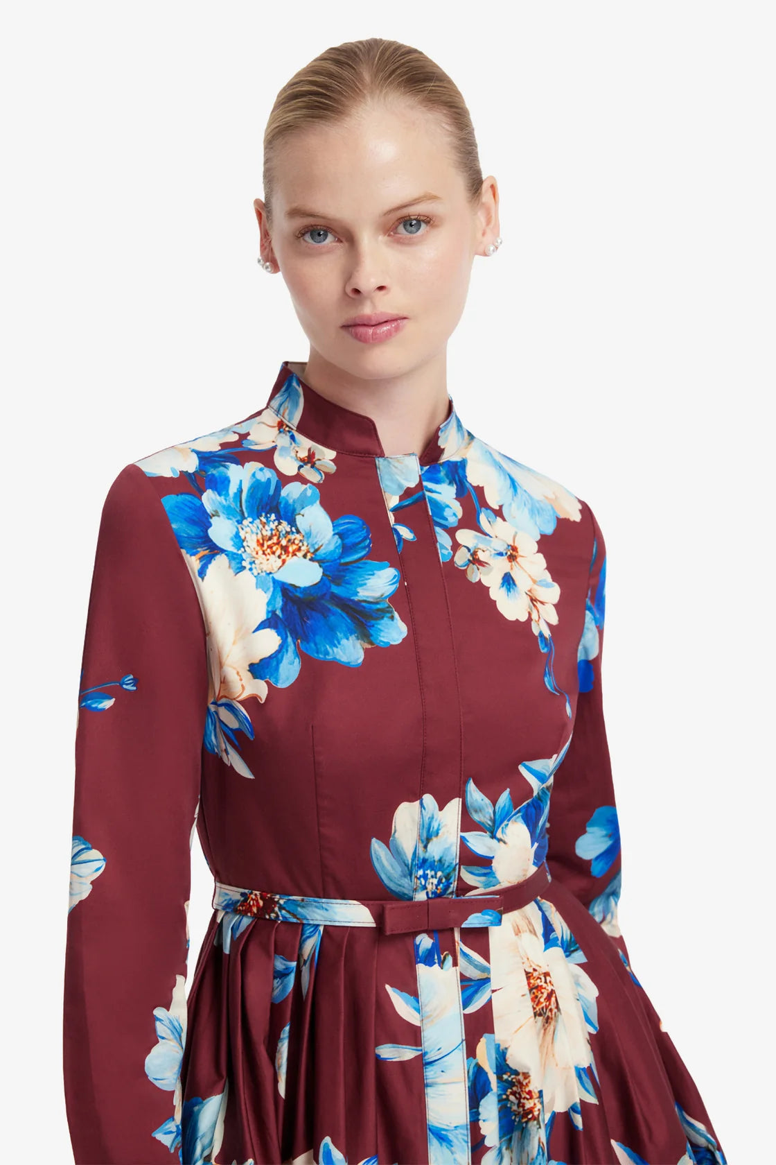 Woman wearing a maroon dress with blue floral pattern on a white background