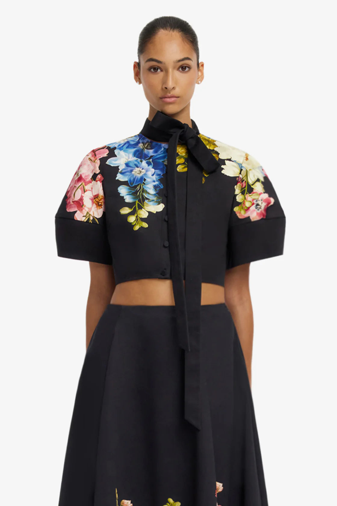 Woman wearing a black outfit with floral sleeves on a white background