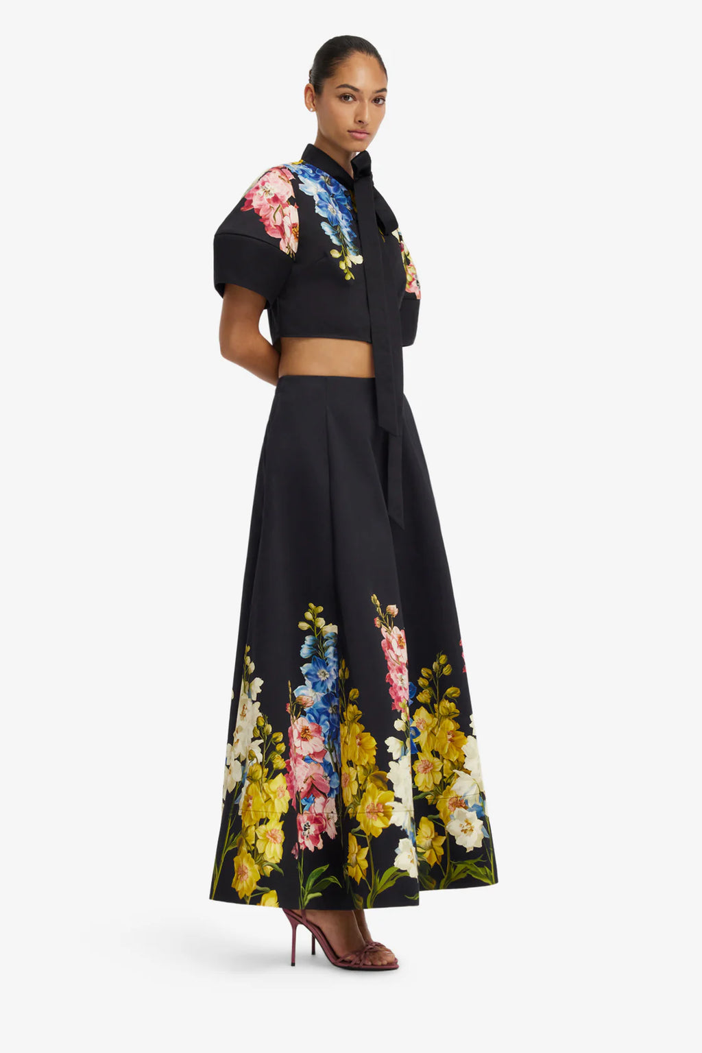 Woman wearing a black outfit with floral patterns on a white background
