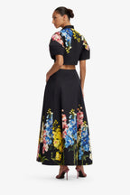 Woman wearing a black outfit with colorful floral patterns on a white background