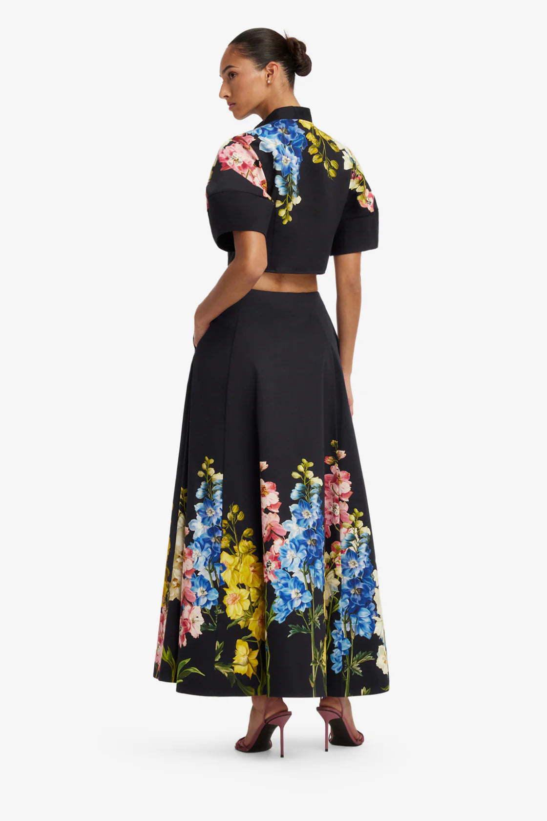Woman wearing a black outfit with colorful floral patterns on a white background