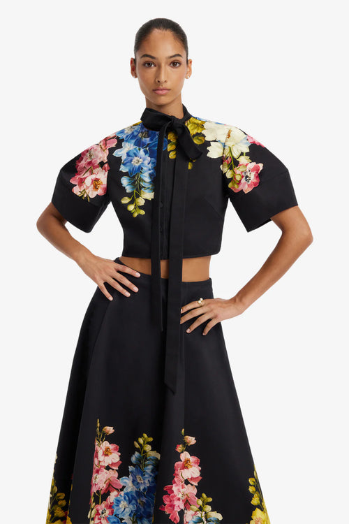 Woman wearing a black outfit with floral embroidery on a white background