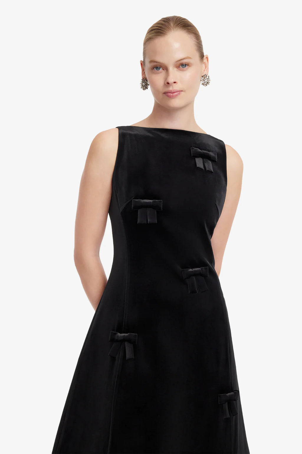Woman wearing a black sleeveless dress with large buttons on a white background