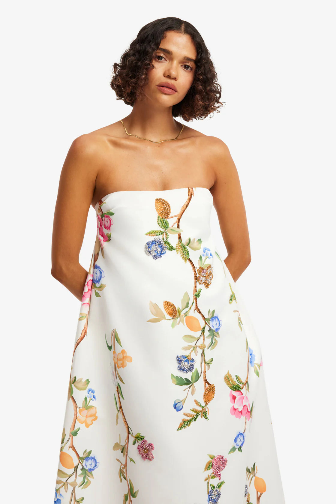 Woman wearing a strapless floral dress against a white background