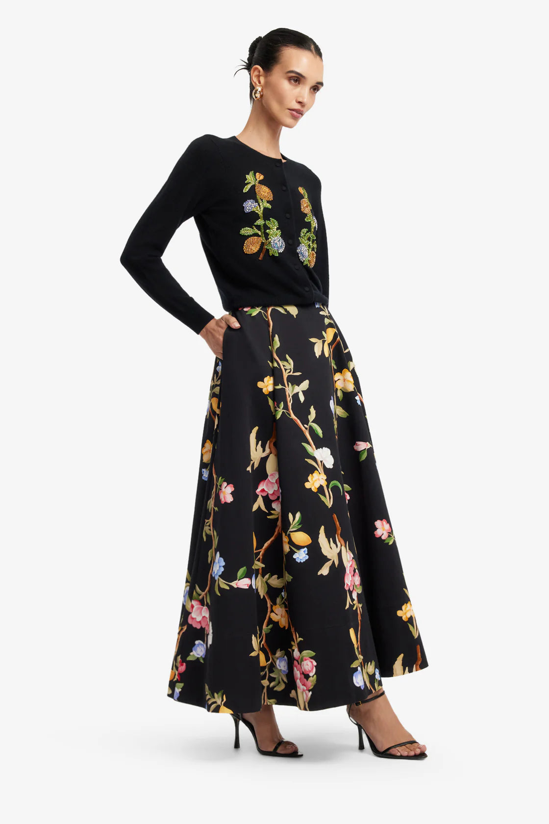 Woman wearing a black floral top and skirt on a white background