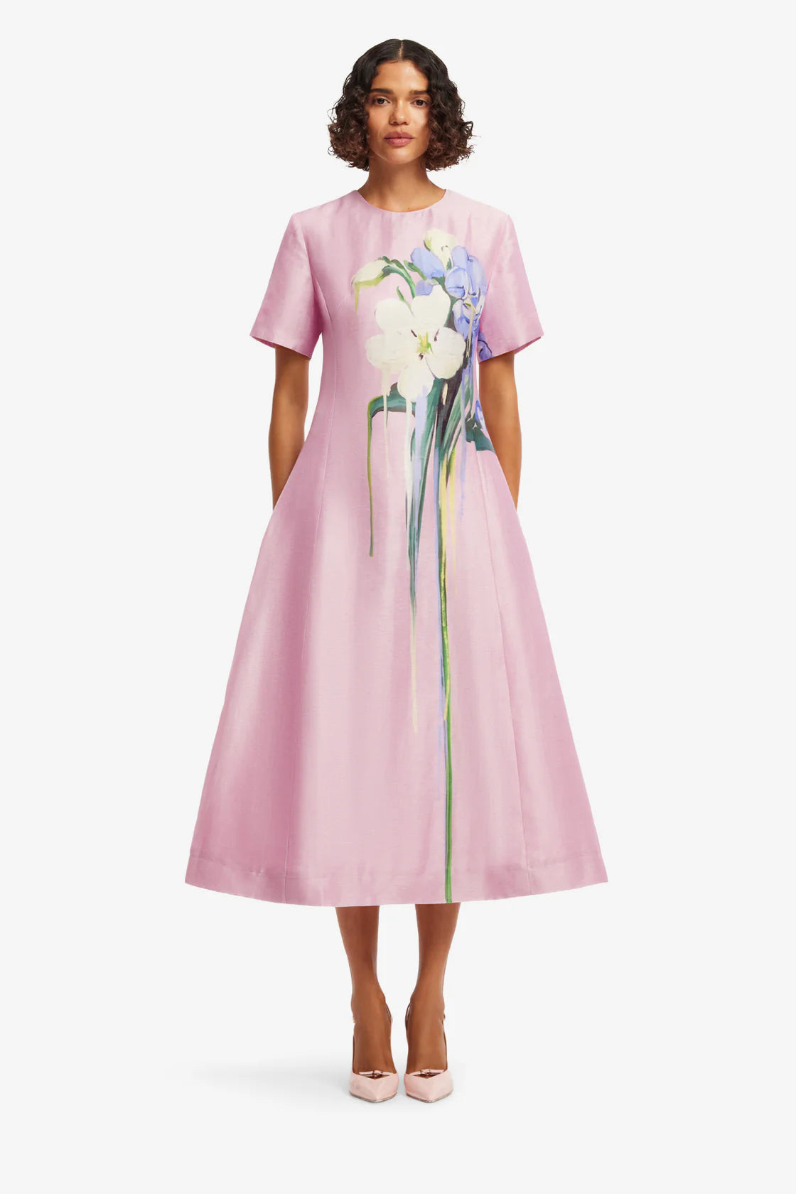 Woman wearing a pink dress with floral design on a white background