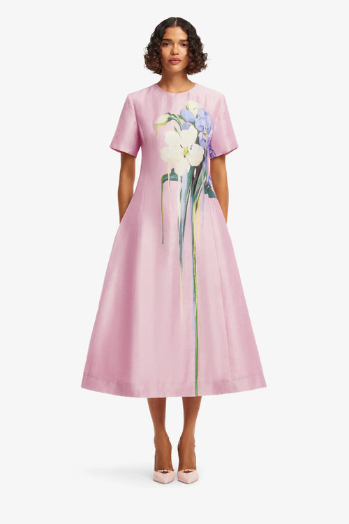 Woman wearing a pink dress with floral design on a white background