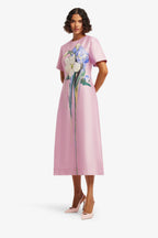 Woman wearing a pink dress with floral design on a white background