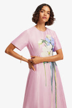 Woman wearing a pink dress with floral design on a white background