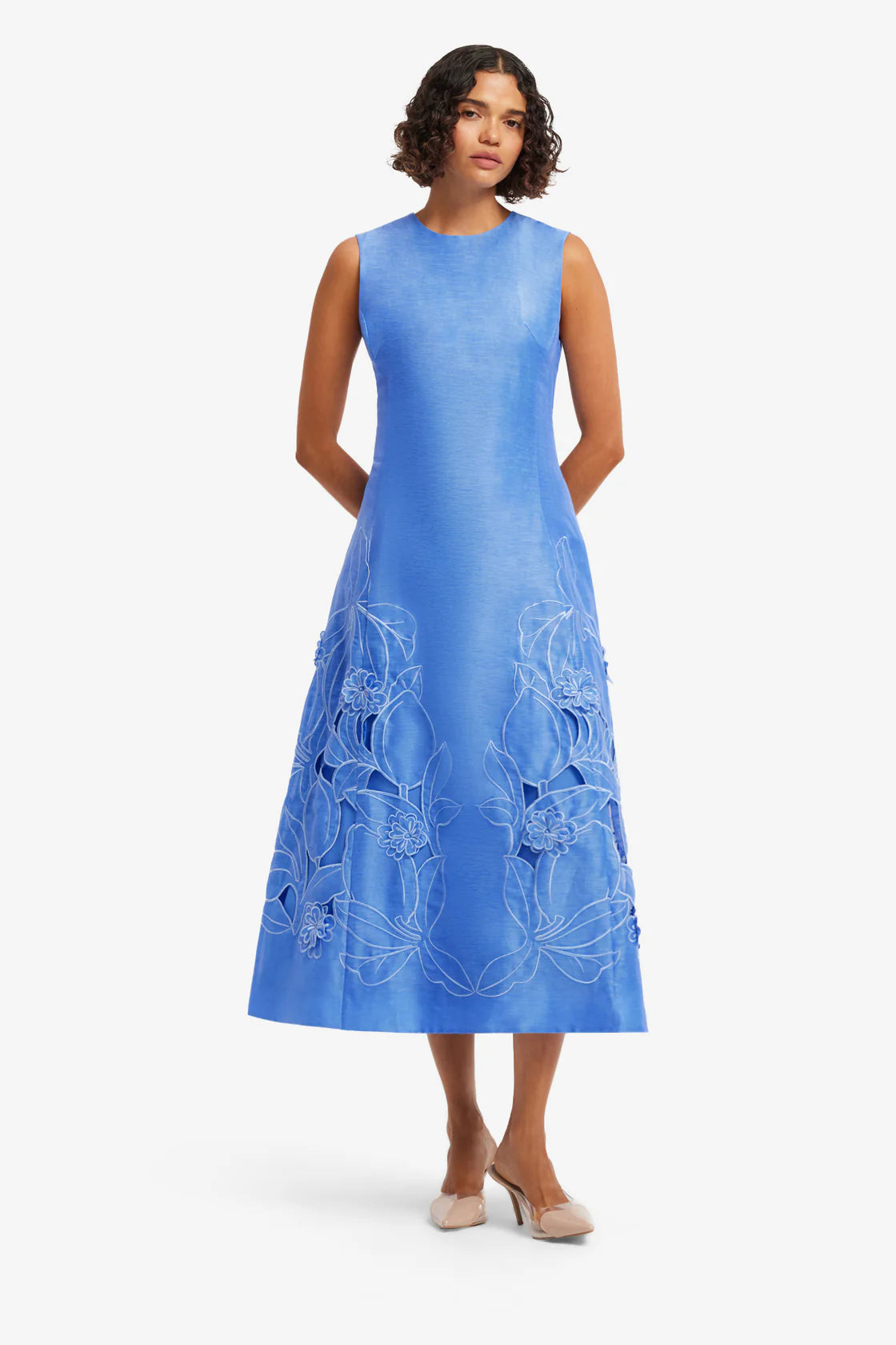 Woman wearing a blue dress with floral patterns on a white background