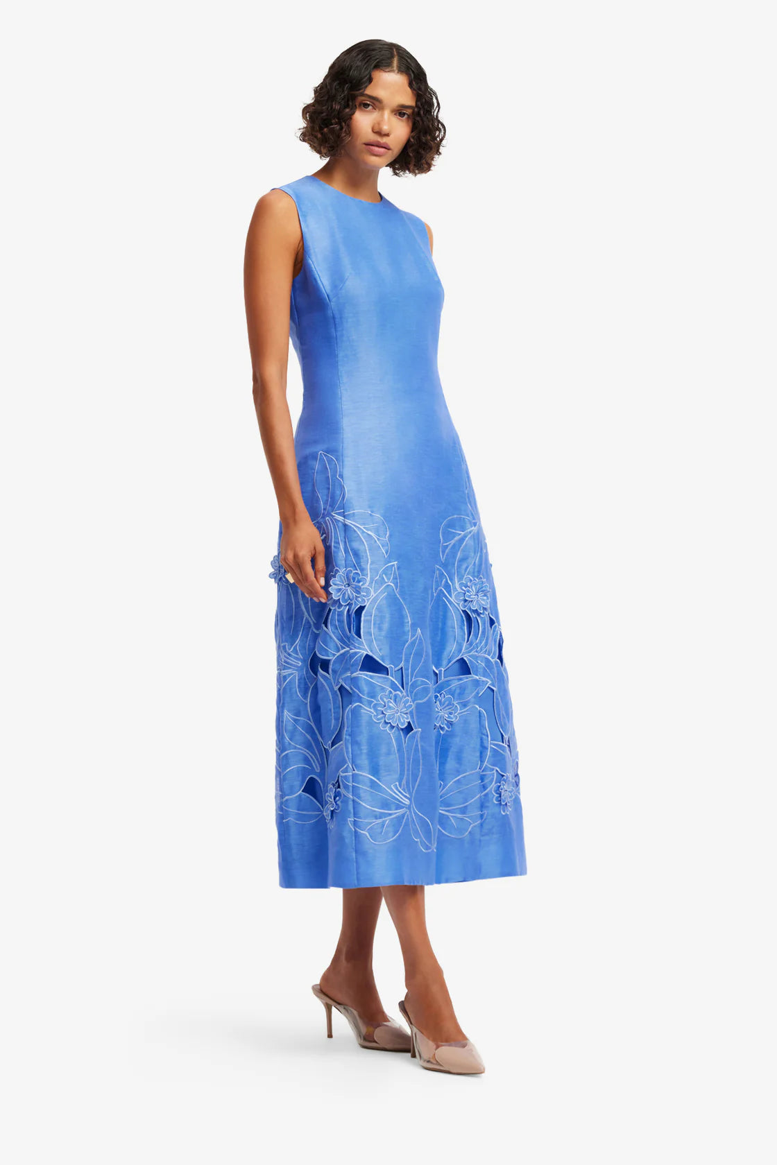 Woman wearing a blue dress with floral patterns on a white background
