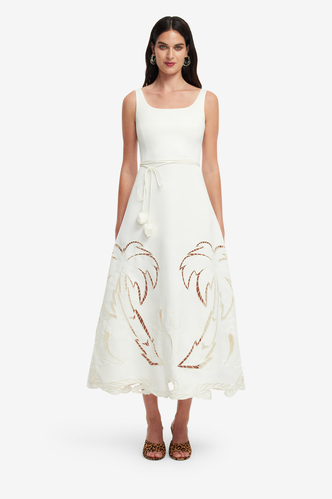 Woman wearing a white dress with palm tree designs on a white background