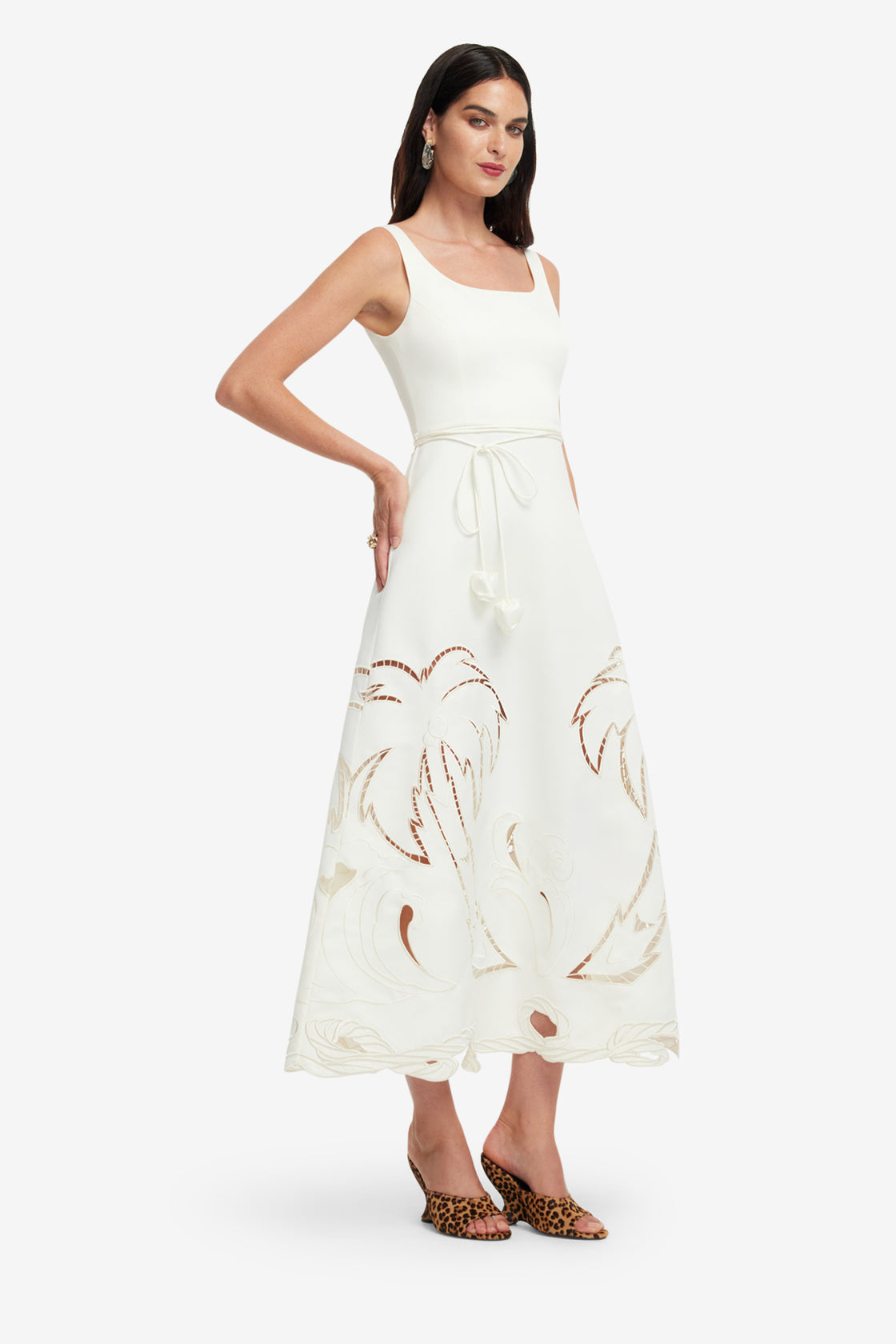 Woman wearing a white dress with palm tree patterns on a white background